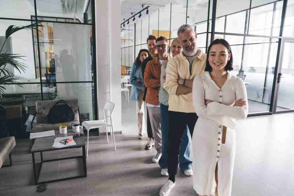 Cheerful multiracial coworkers lining up in row in workspace